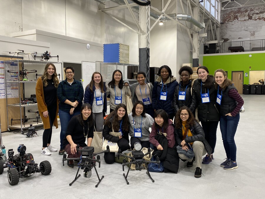 a group of people posing behind robots in a large warehouse