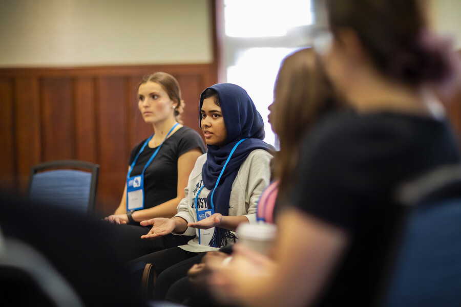 people sitting in a group talking with the main speaker in focus