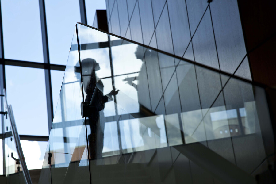 Two figures having a discussion near a stairwell in reflection of glass in a Penn Law building