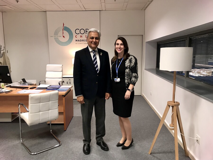 Two peopel standing in an office space. On the wall behind them are the words "COP, Chile, Madrid." 