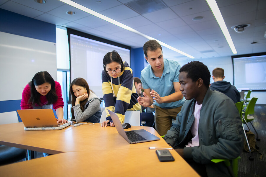 Josh Nadel and a group of students working on laptops around a table