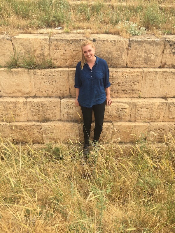 A person leans up against ancient mud walls at an archeological dig