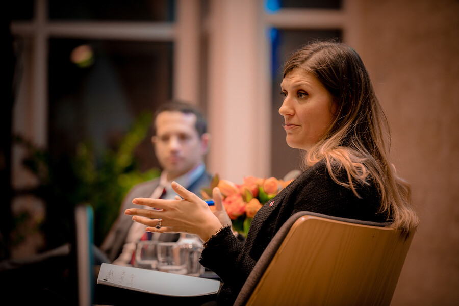 person seated in chair on a stage talks to someone outside of picture