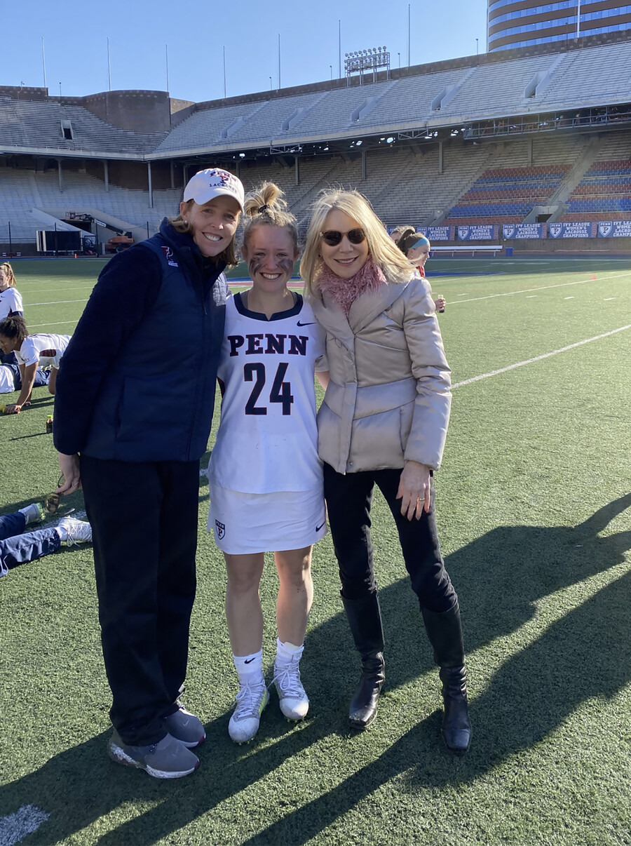 Karin Corbett, Gabby Rosenzweig in uniform, and President Gutmann hug on the field