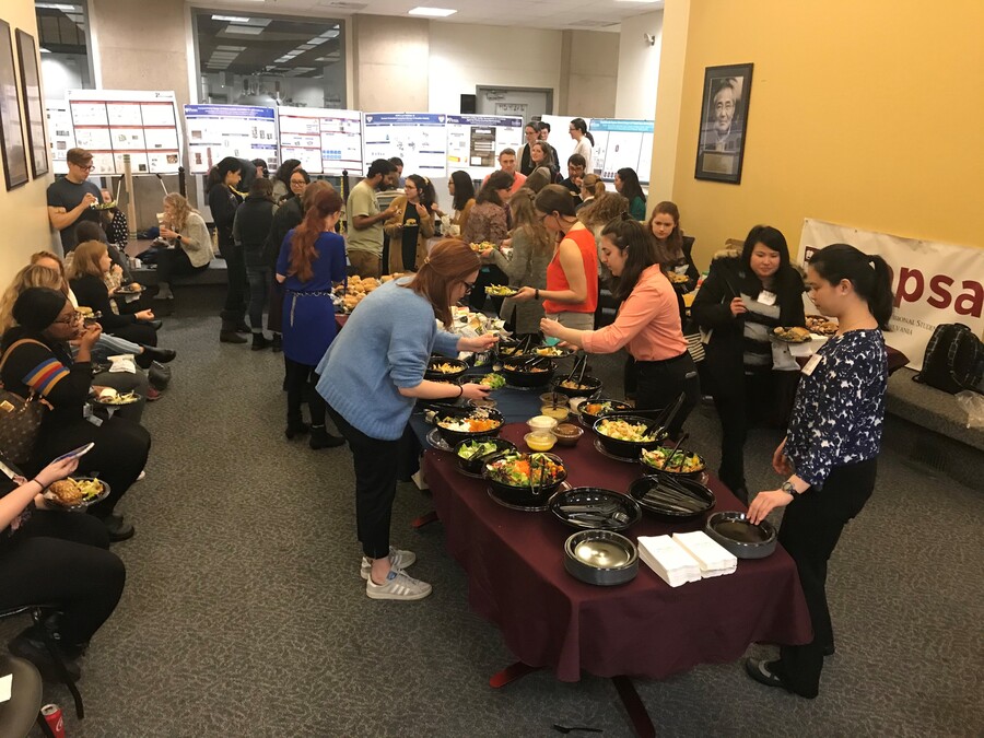 people gathered around a table getting food with posters and signs in the background
