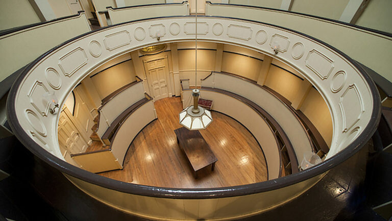 a circular room with a lamp and a table in the center