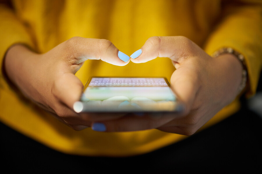 Hands holding smartphone with thumbs poised over screen getting ready to type something.