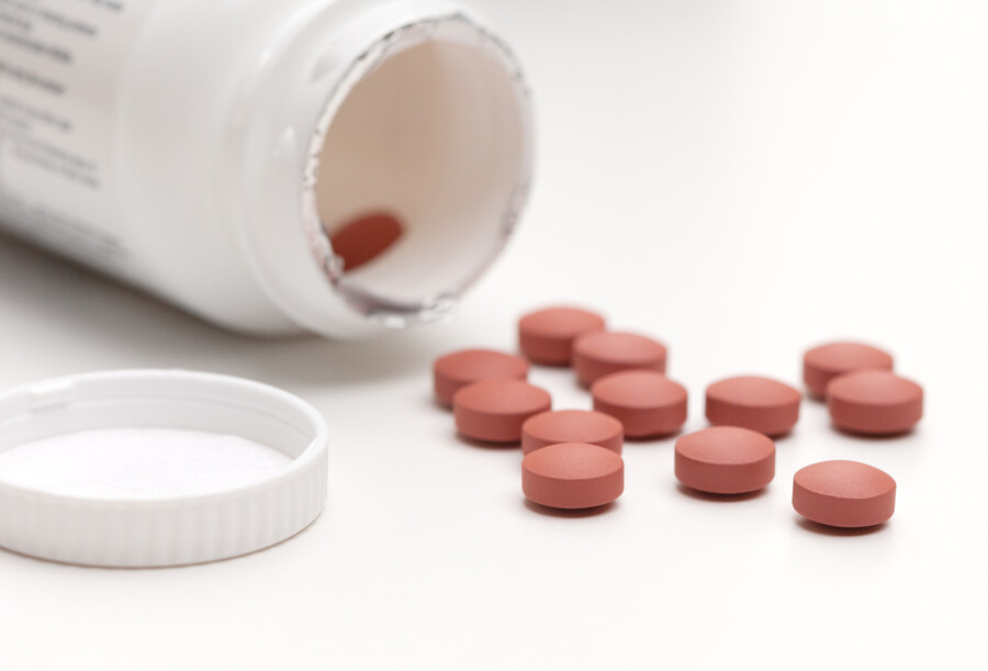 ibuprofen pills are scattered in front of an opened bottle of ibuprofen