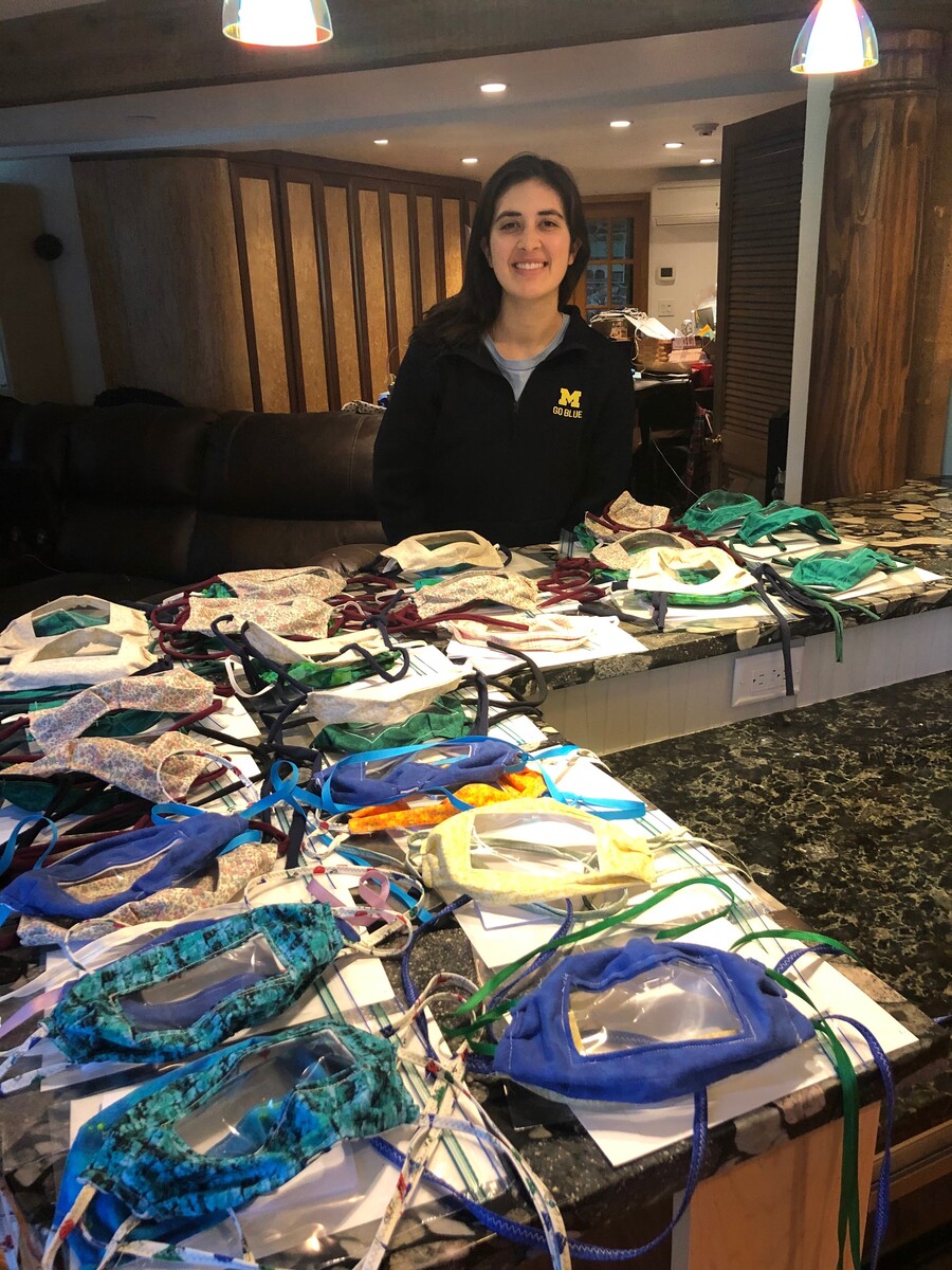 A person standing behind a counter full of face masks with clear fronts. 