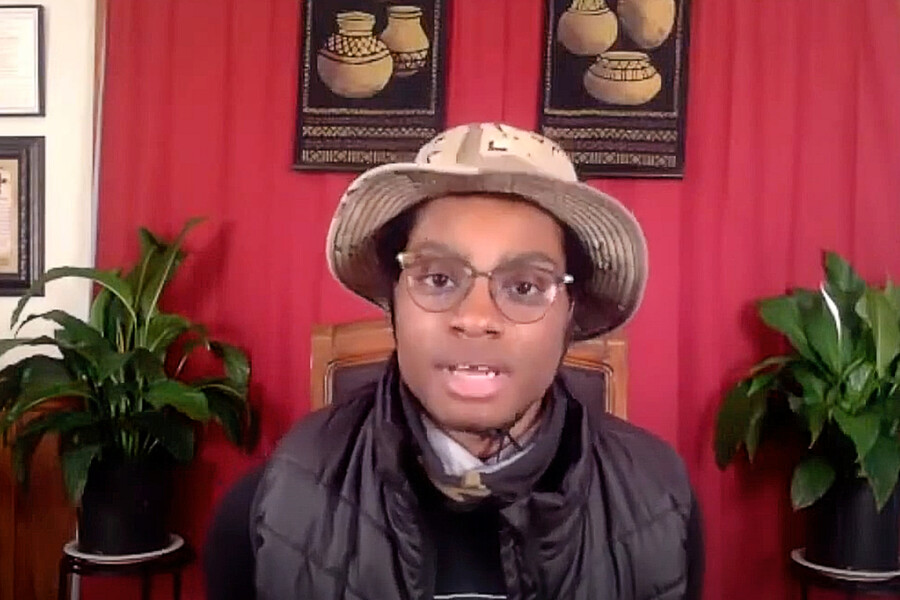 Student wearing a hat and glasses talking