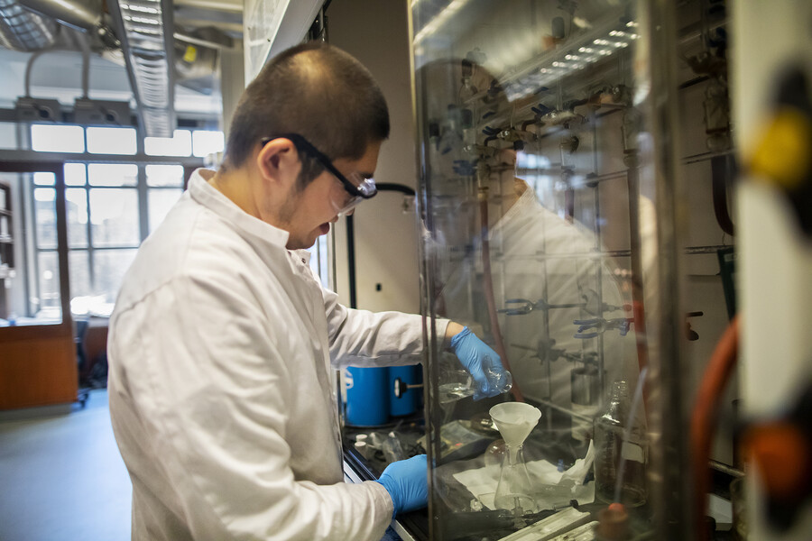 qiuran wang pouring liquid into a funnel inside a laboratory