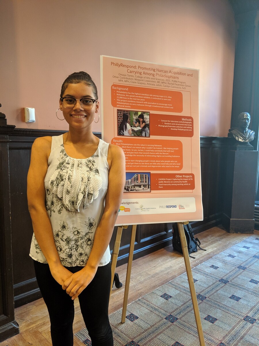 Student stands next to research poster