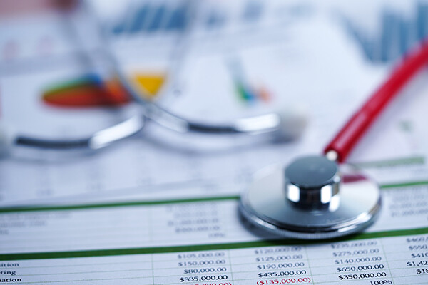 Stethoscope laying on top of financial spreadsheets