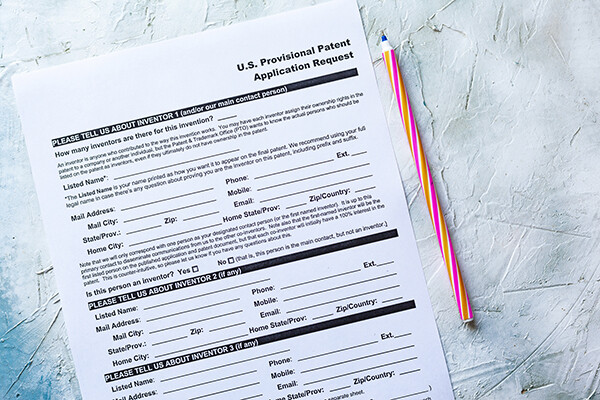 Blank form on a table beside a pen that reads “U.S. Provisional Patent Application Request.”