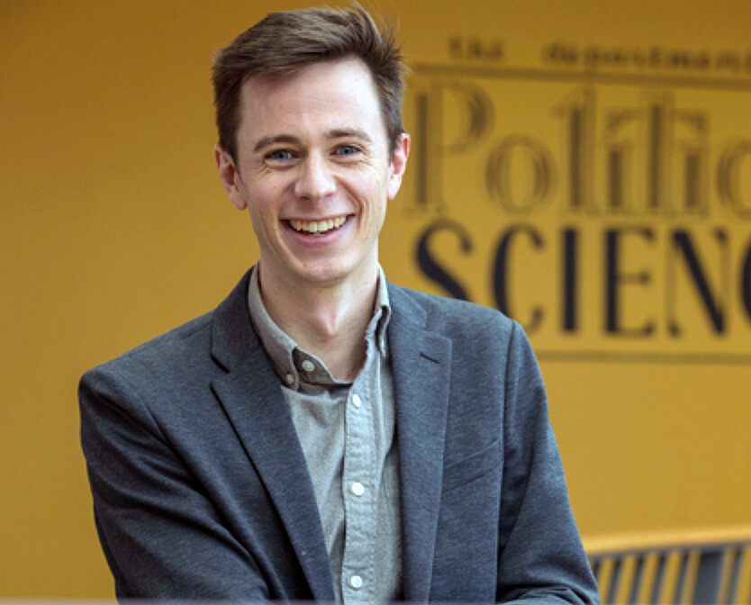 Person in front of yellow wall smiles at camera