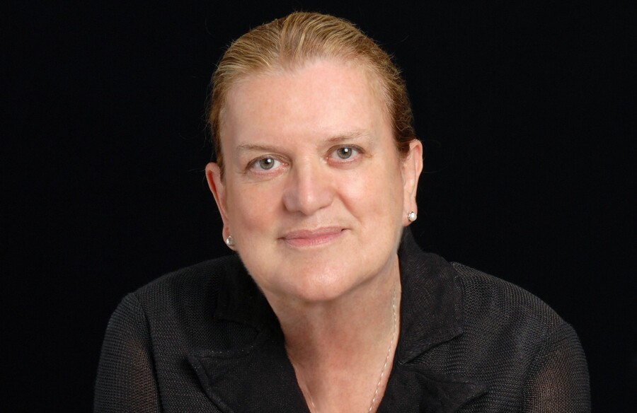 Up close headshot of a person in front of a black background. 