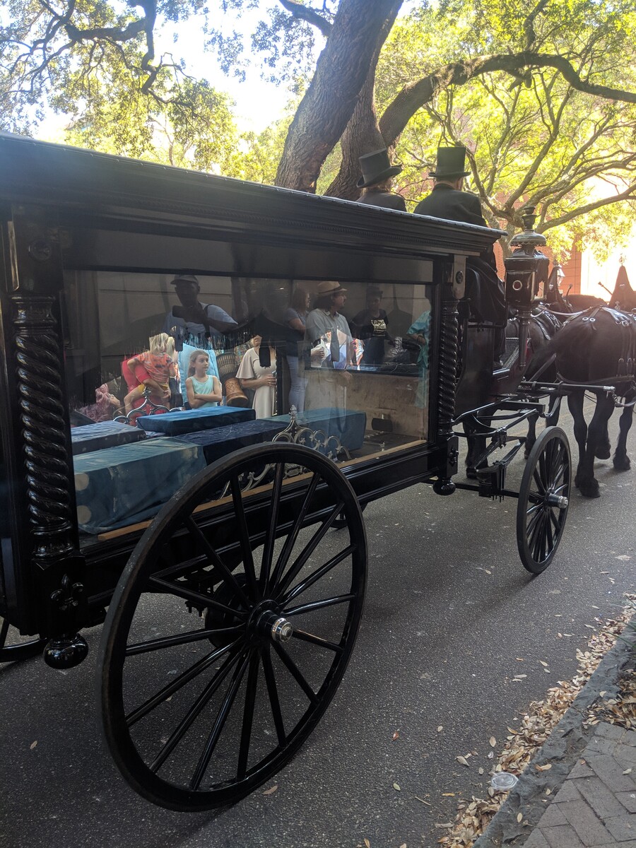 Horse-drawn carriage walking down a street through a crowd of people. 