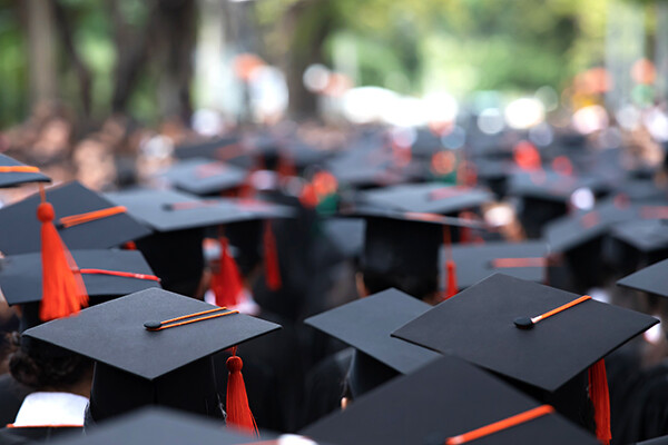 Crowd of graduates wearing mortarboards walking in procession at commencement.