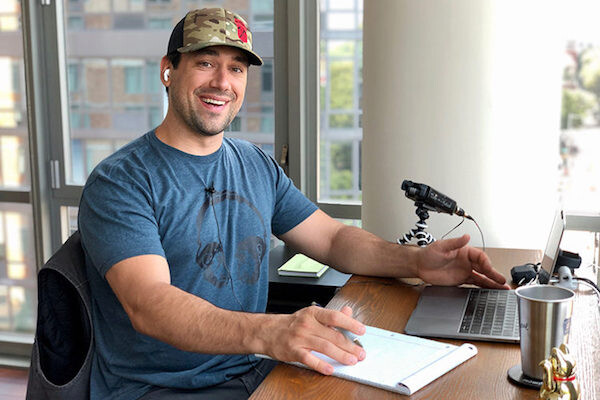 Matt DeVivo sitting at a table with a computer and podcast equipment.