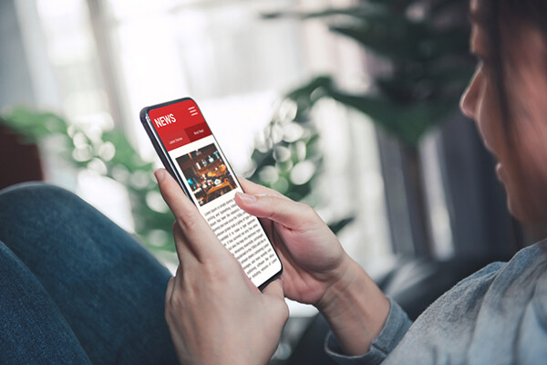 Closeup of person holding a smartphone with a news article on the screen.