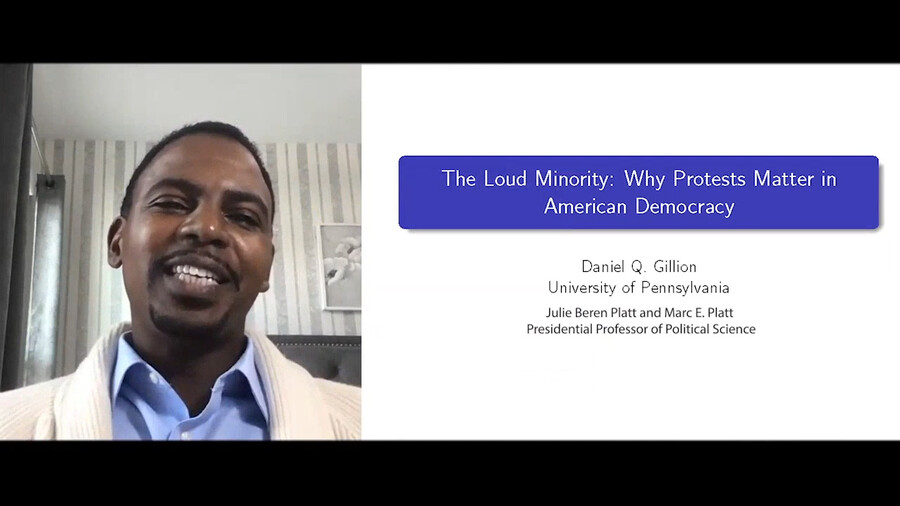 Daniel Gillion speaks at Engaging Minds while presentation on his left reads: "The Loud Minority: Why Protests Matter in American Democracy"