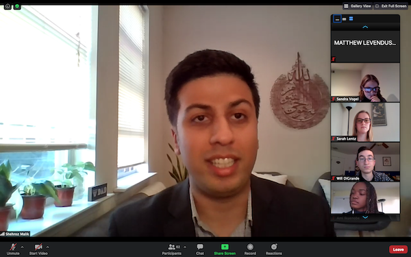 Person seen in a computer screen on a zoom call while four others are in smaller windows on the screen's right side