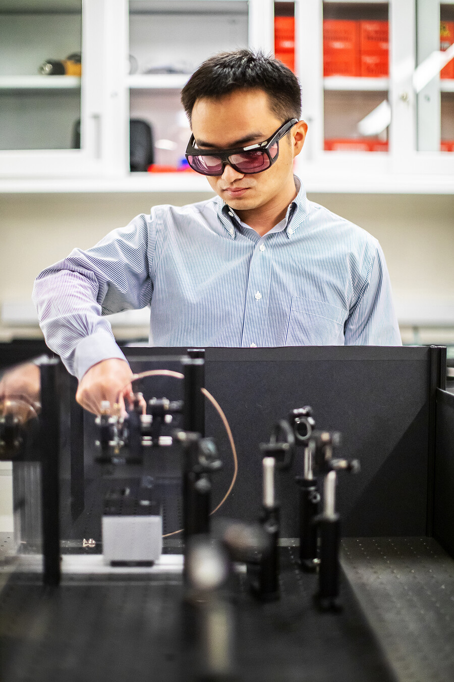 a person in a lab adjusting a lens on an optics table