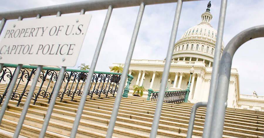 Police fence at foot of stairs to U.S. Capitol with a sign that reads PROPERTY OF U.S. POLICE.