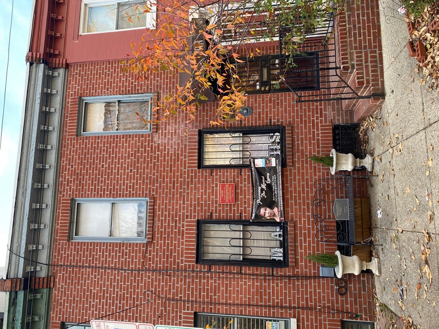 The brick facade of a rowhouse with blue trim