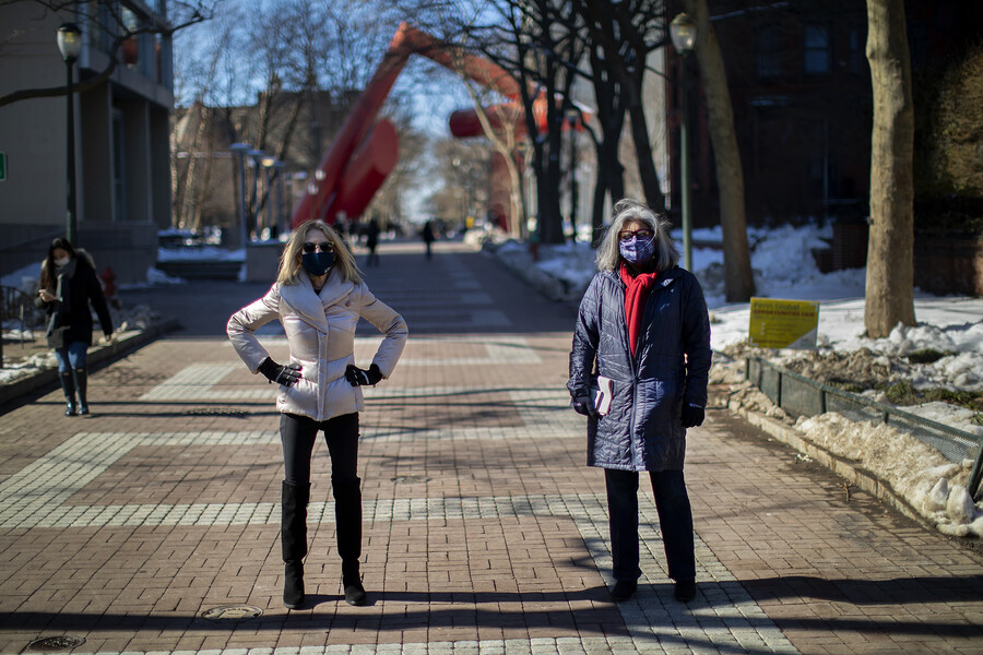 Penn President Amy Gutmann with Mamta Accapadi standing in the sunlight on Locust Walk wearing face masks.