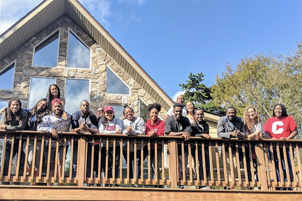 Group of BLSA students standing by a railing on an outdoor porch in the sunshine.