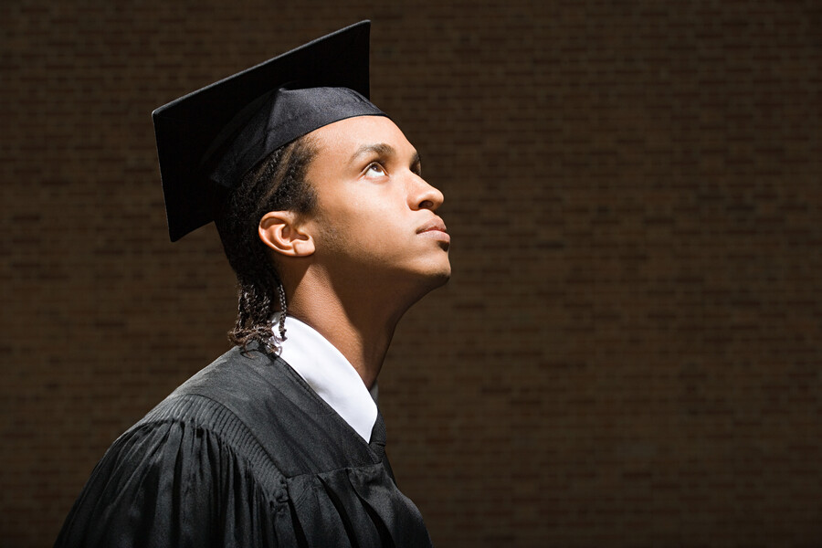 College graduate wearing a cap and gown looking anxious.