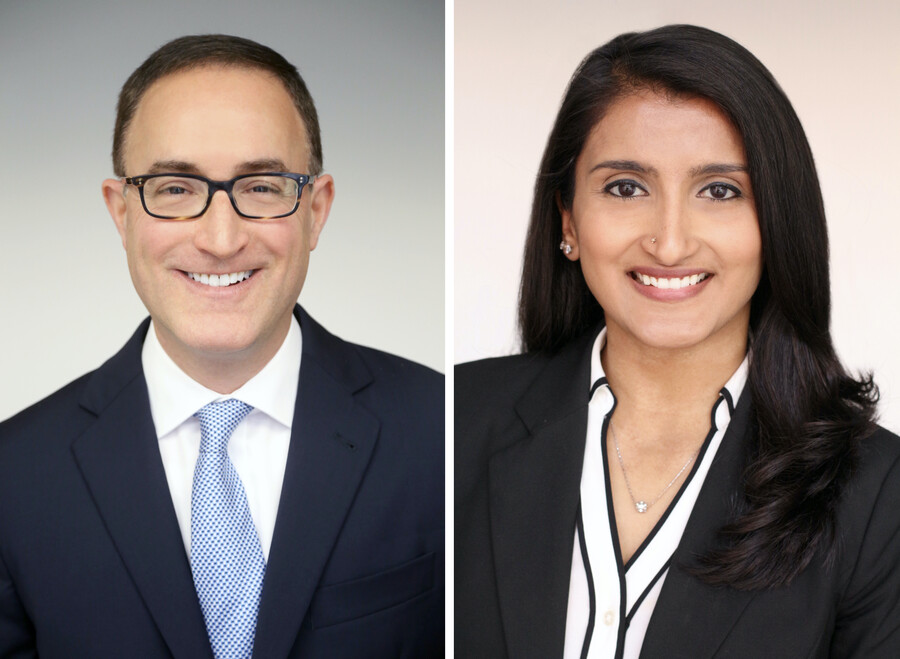 Headshots of two people. On the left is a person with glasses wearing a blazer, white shirt and blue tie. On the right is a person in a black blazer, black-and-white blouse and visible necklace. Both are smiling.
