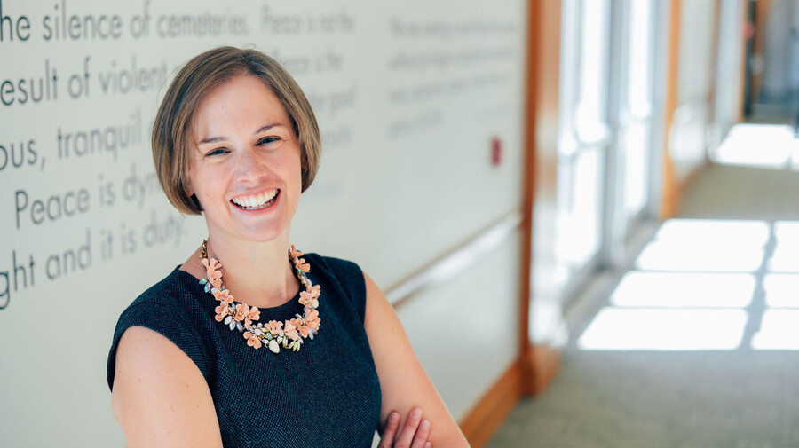 Emily Largent smiles in front of a white board.