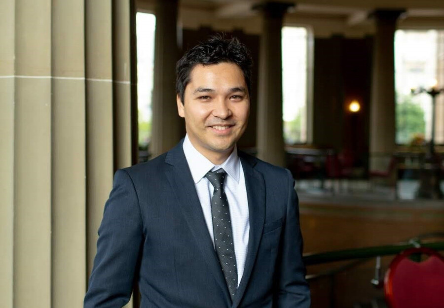 Damian Pang standing, smiling, in a suit.