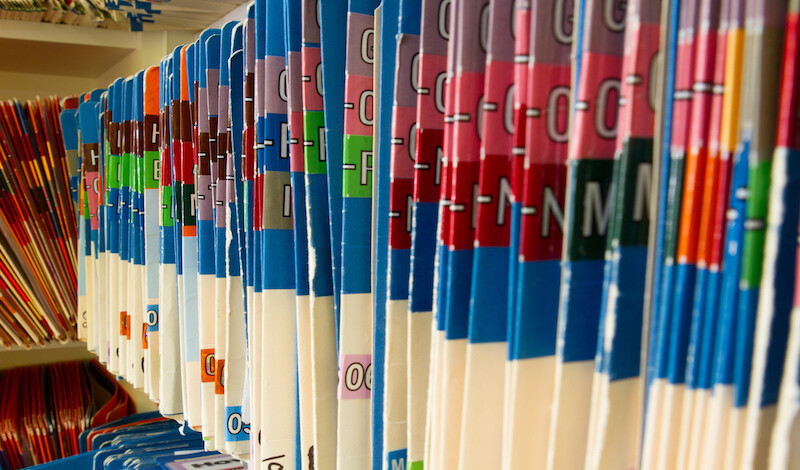 Folders full of alphabetized medical records on a shelf.