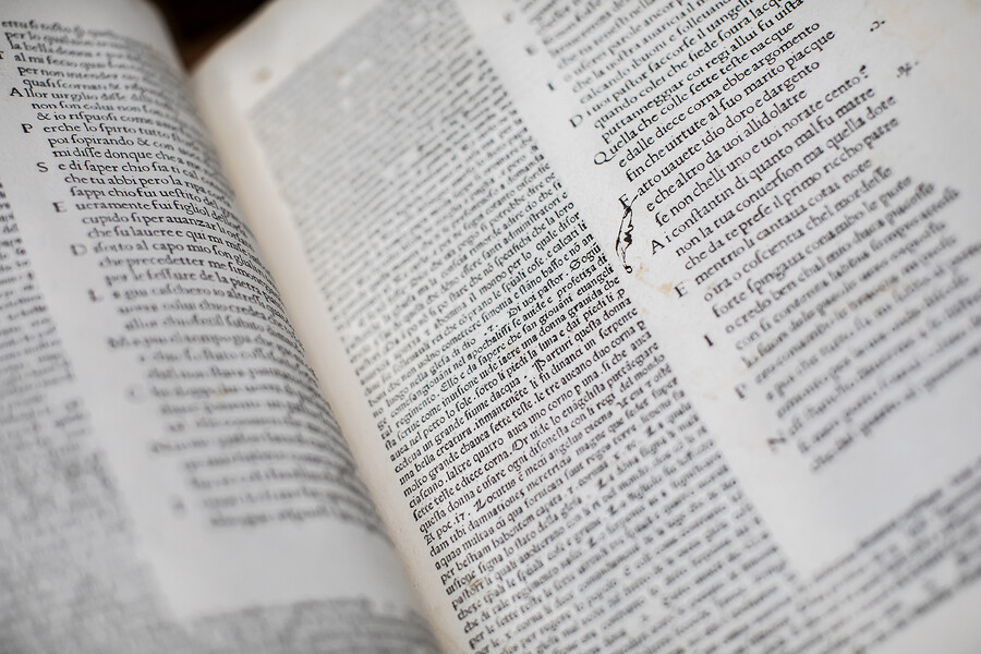 An old book open to a page with a finger drawn in the margin