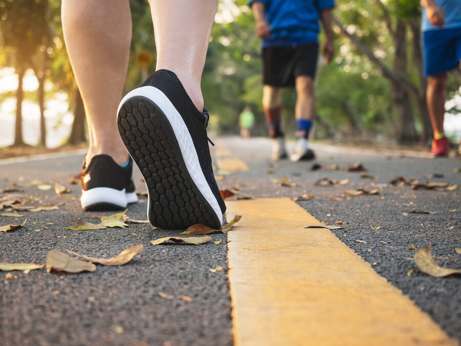 Three people as seen from the ground wearing running shoes on a paved running trail.