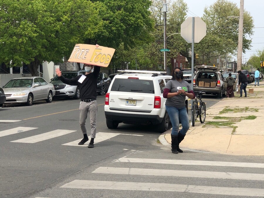 Person holds up sign that says "Free Food" at a distribution event