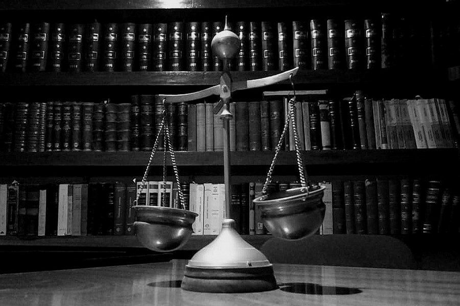 A close up to the an ornamental scale in an office with law books on shelves behind it.