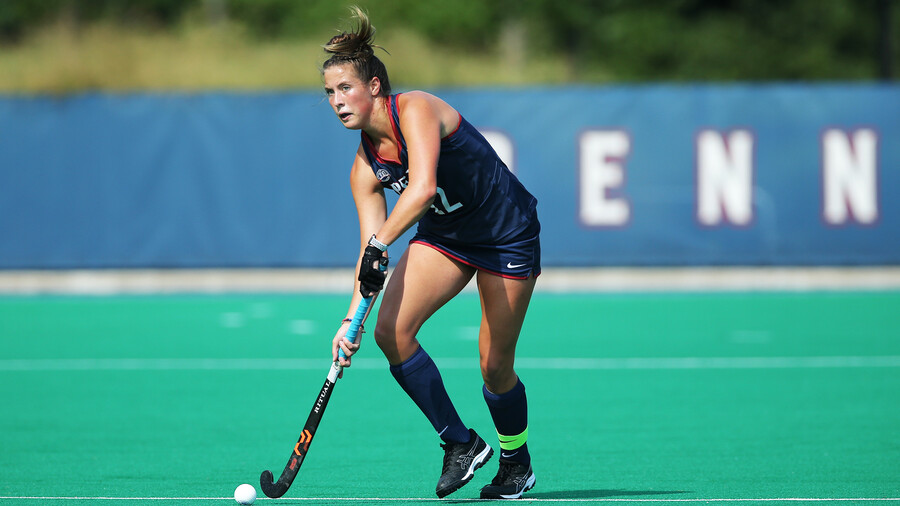Banks dribbles the ball up the field with her stick during a game.