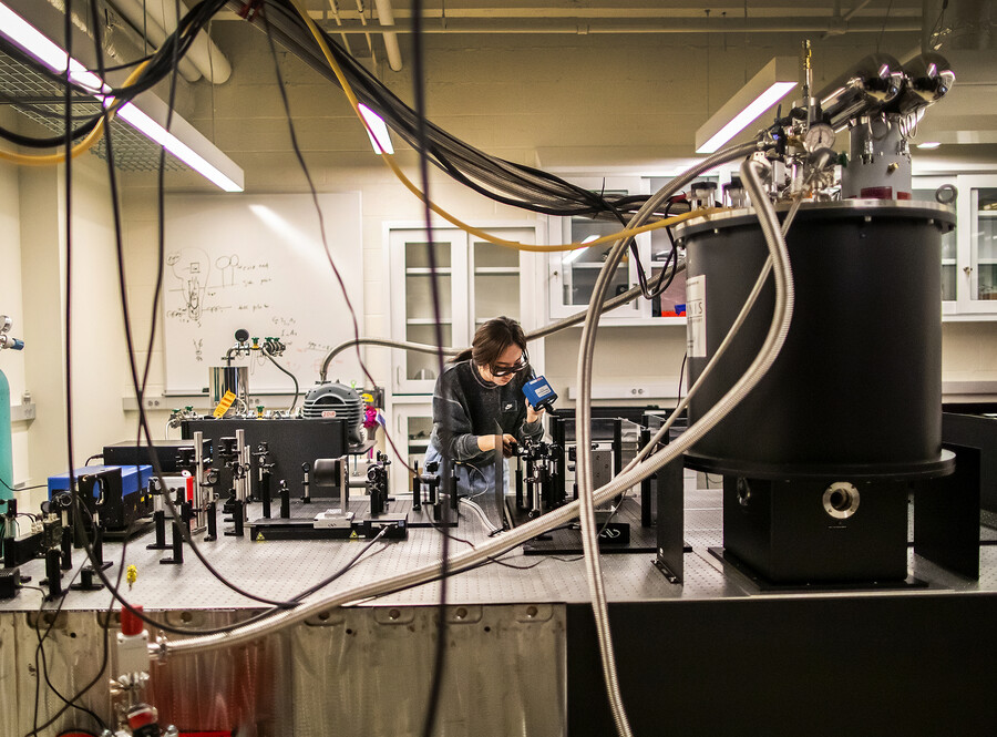 a person looking through a lens at a device in a physics lab