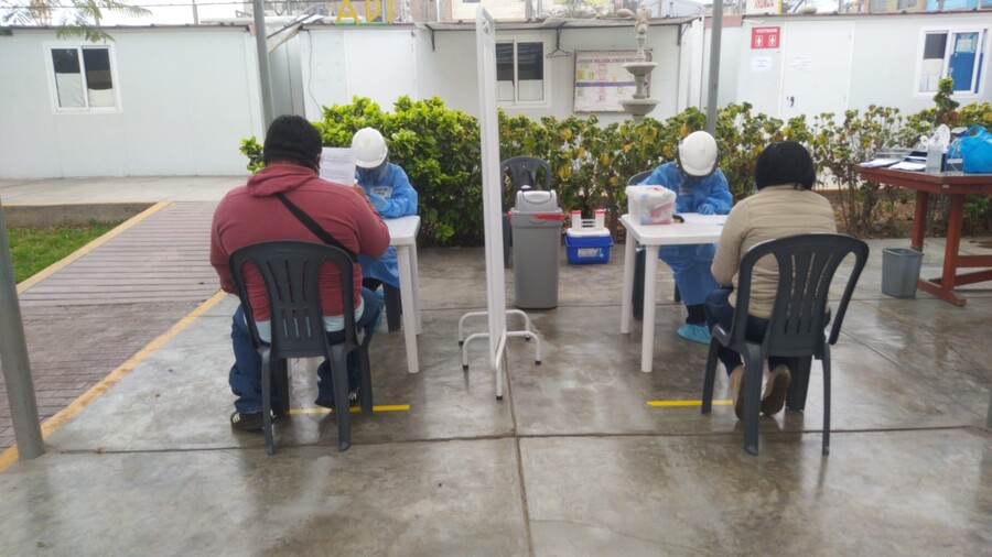 Study subjects sit opposite researchers in personal protective equipment during a study of COVID in Peru