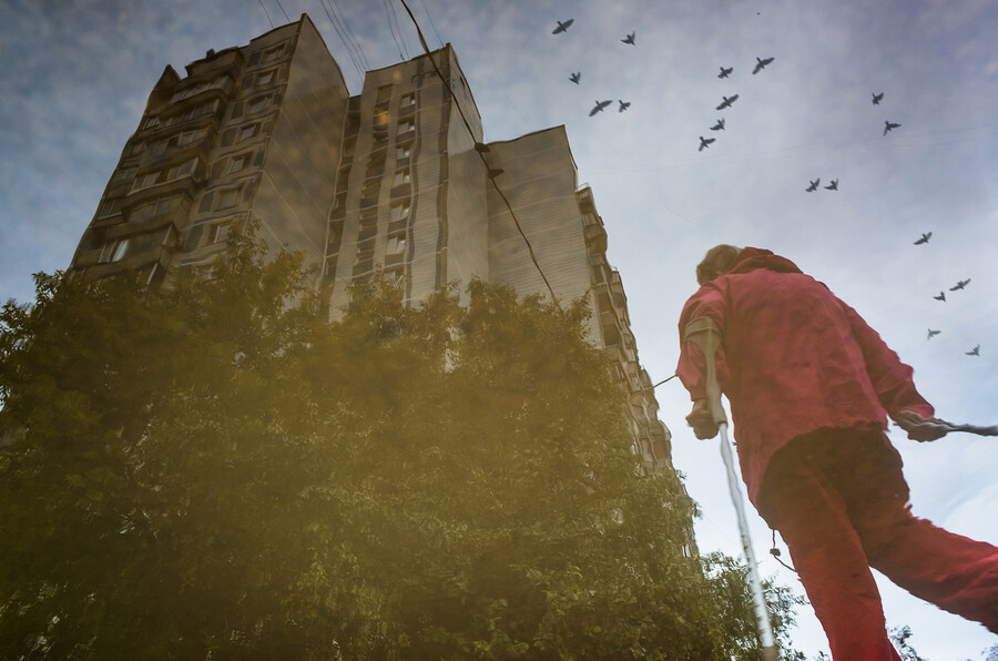 Person walking with cane past a tall apartment building.
