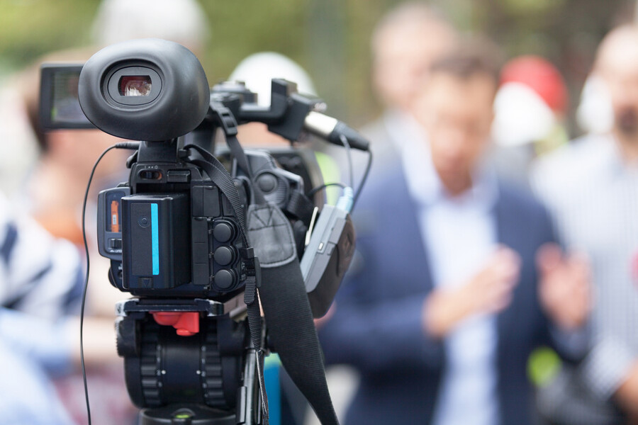 TV camera in front of a crowd of people.