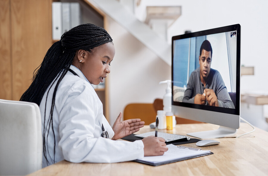 A patient having a telemedicine appointment with a doctor via a desktop computer screen.