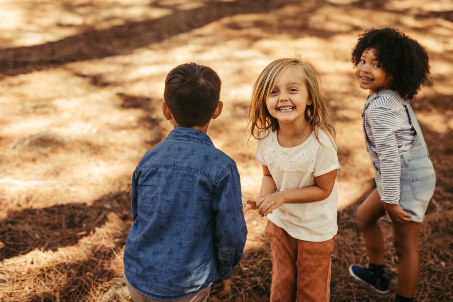 Three children playing outside in the sunshine.