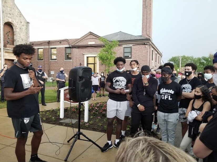 Lucas Monroe looks down at the notes on his phone, addressing a crowd. 