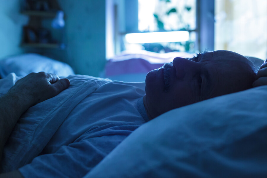 Senior person lying in bed in the daytime.