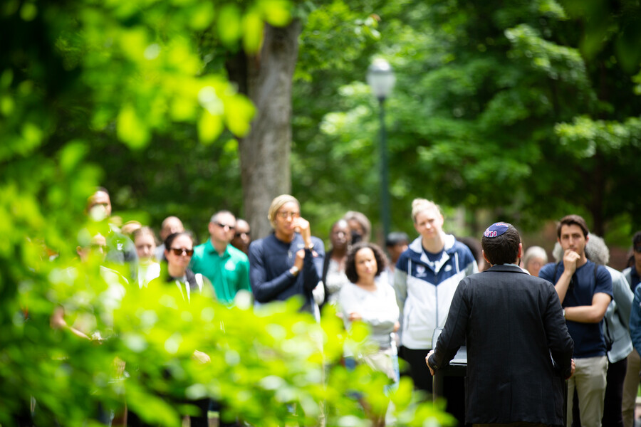 View of crowd at Penn’s gun violence vigil with tree leaves.
